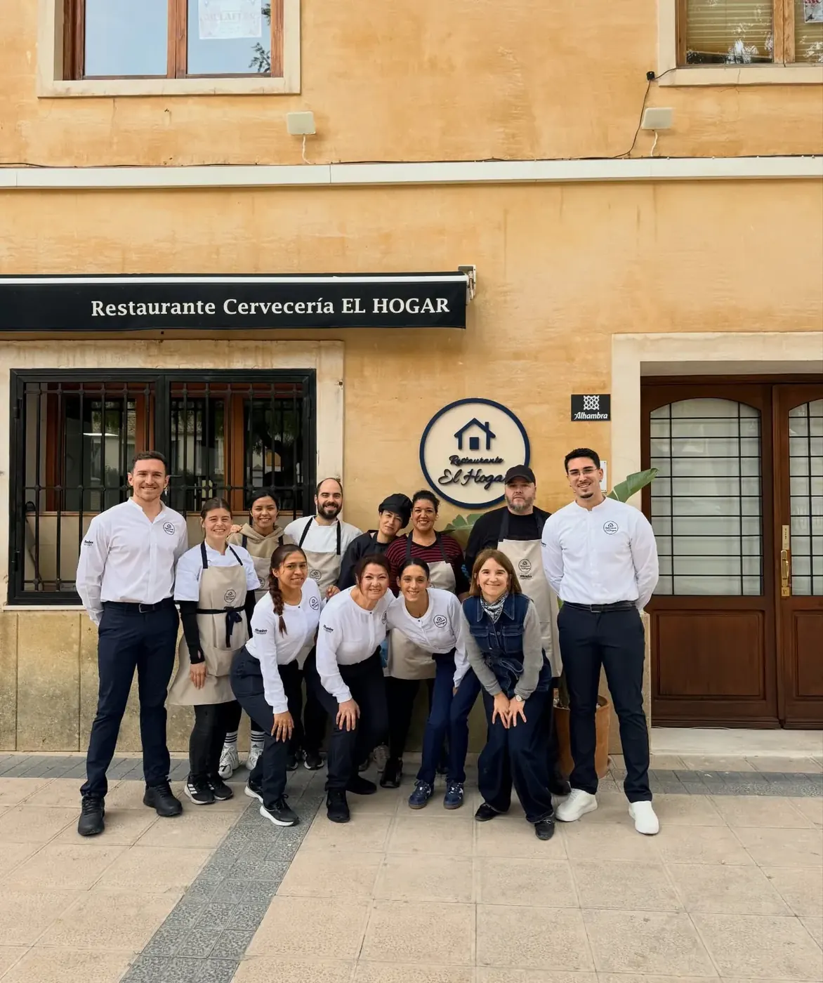 El equipo del Restaurante El Hogar posando en la puerta del local, bajo el rótulo del restaurante